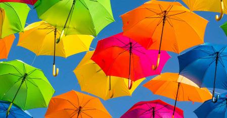 Deine Versicherung bunte regenschirme vor blauem Himmel