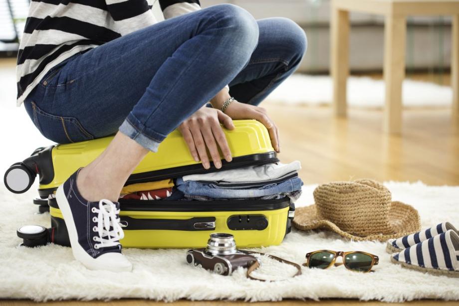 au pair sitzt auf koffer um ihn zu schliessen